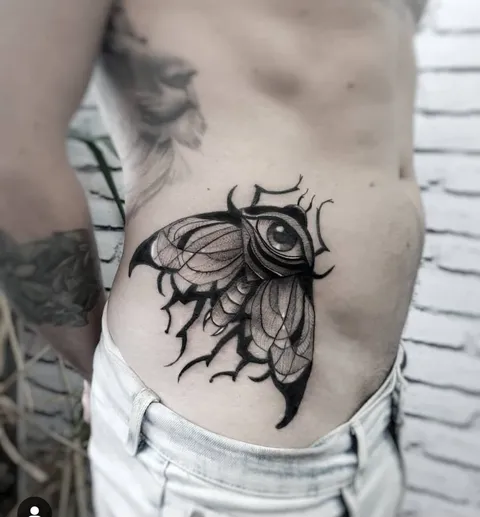 Mariposa com um olho no centro e asas com pontas em preto sólido, na lateral do tronco