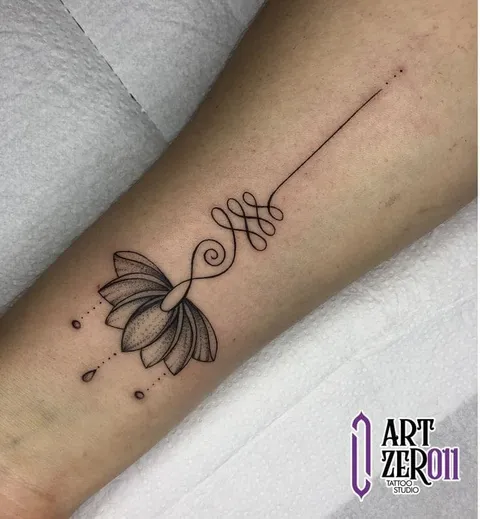 Flor de lótus sombreada com unalome e pontilhado, em traço fino no antebraço