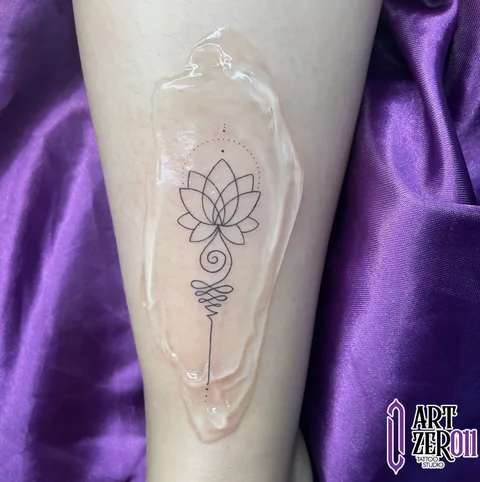 Flor de lótus com unalome (espiral que termina em linha reta) em traço fino, na perna