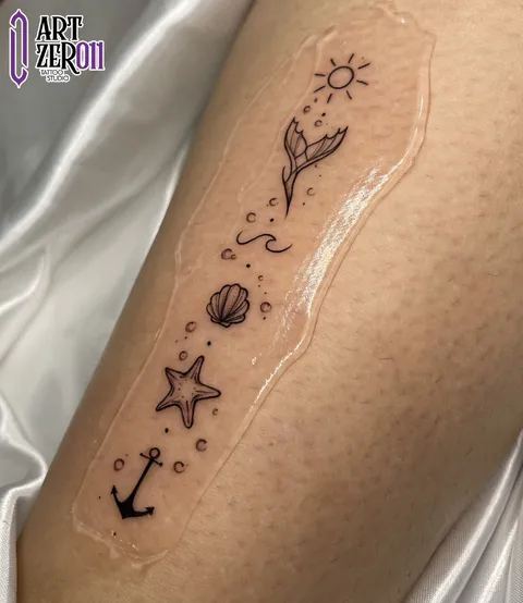 Sol, cauda de baleia, ondas, concha, estrela-do-mar e âncora em traço fino, em linha no braço