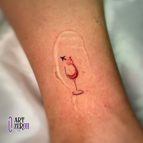 Taça de vinho tinto com um pequeno avião, em traço fino com detalhe em vermelho