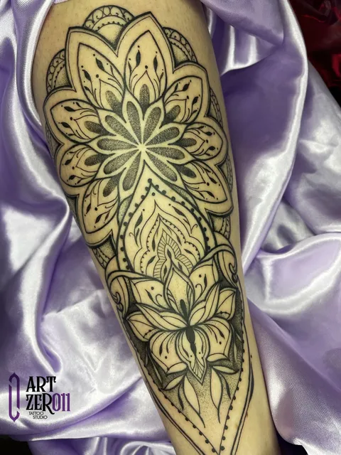 Mandala com flor de lótus e ornamentos em preto, ocupando o antebraço