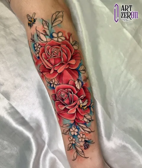 Rosas vermelhas com flores azuis e abelhas, em tatuagem colorida no antebraço