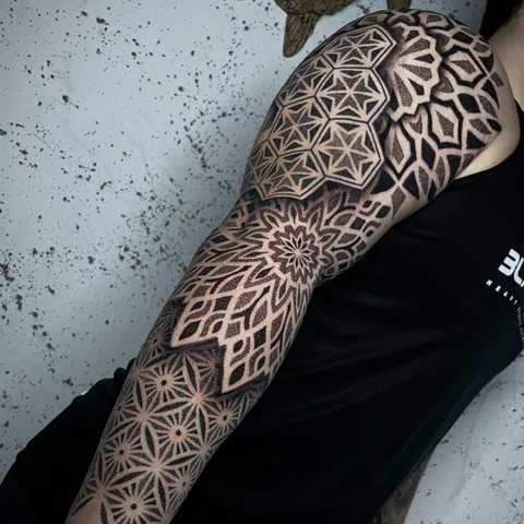 Braço fechado do ombro ao punho com mandalas e padrões geométricos em pontilhismo preto
