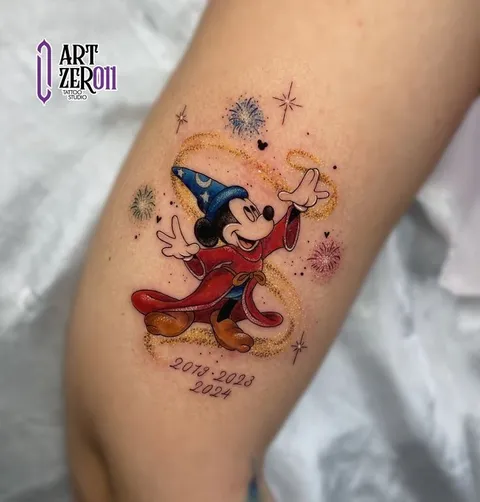 Mickey vestido de feiticeiro, colorido, com fogos de artifício e brilho dourado em volta e datas em letra cursiva embaixo