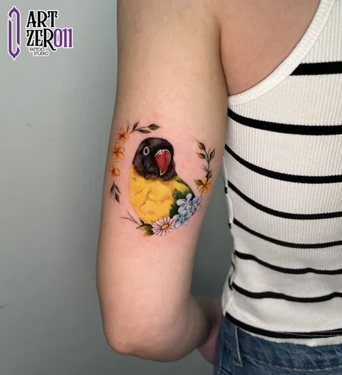 Agapórnis (pássaro) colorido dentro de uma guirlanda de flores, no braço