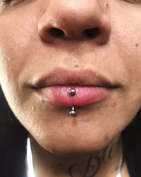 Labret vertical no lábio inferior, com bolinhas de metal nas duas pontas