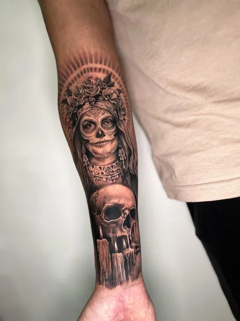 Catrina com coroa de flores e caveira com vela, em realismo preto e cinza, no antebraço