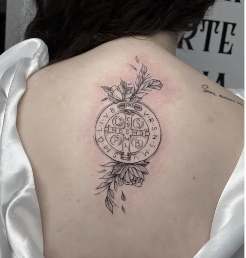 Medalha de São Bento em traço fino com flores, no meio das costas